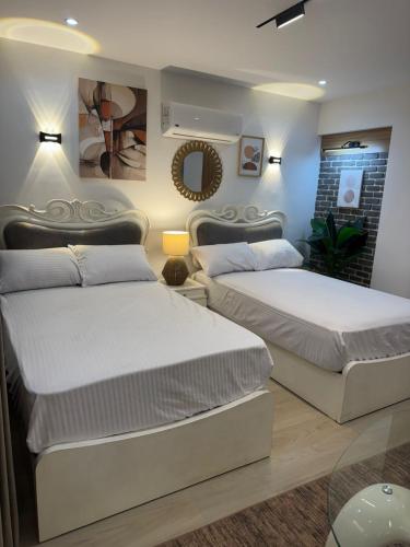a bedroom with two beds and a mirror at Luxury 2BR Pool View Apartment Hotel Style in New cairo