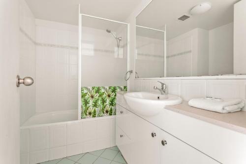 a white bathroom with a sink and a shower at Kirra Palms Holiday Apartments in Gold Coast