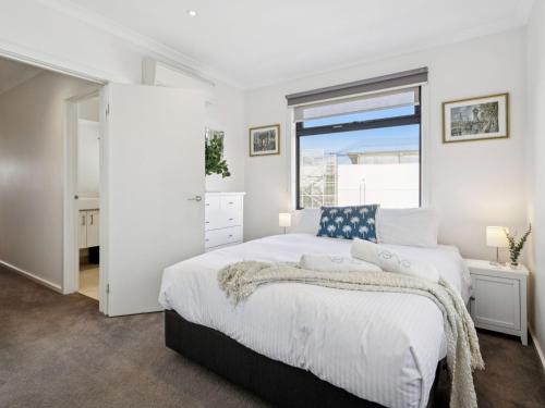 a white bedroom with a large bed and a window at Azura on Gordon in Mornington