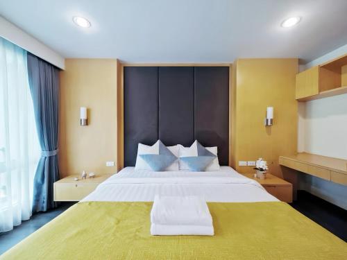 a bedroom with a large bed with a yellow blanket at Residence One Bangkok in Bangkok