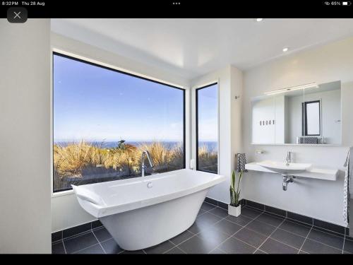 a bathroom with a tub and a sink and a large window at Oceanview Haven B&B in Dunedin