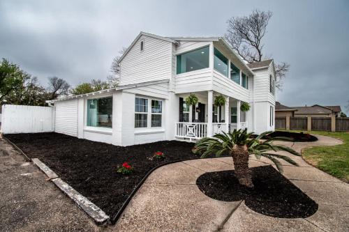 a white house with a palm tree in the front yard at Coastal Oasis - Beautiful Ocean Views Awaits in Corpus Christi