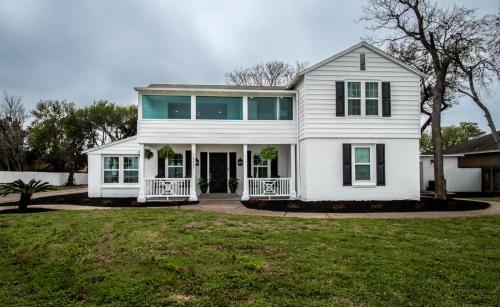 a white house with a porch and a yard at Coastal Oasis - Beautiful Ocean Views Awaits in Corpus Christi