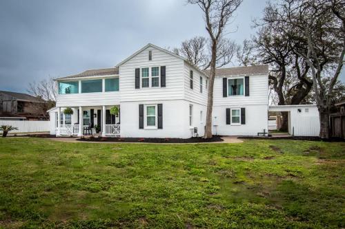 a white house with a tree in the yard at Coastal Oasis - Beautiful Ocean Views Awaits in Corpus Christi