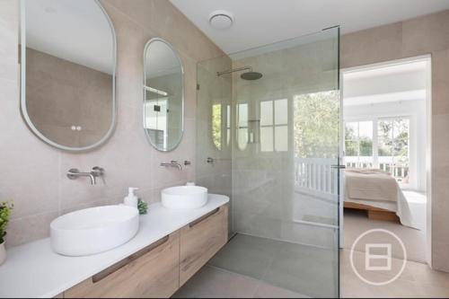 a bathroom with two sinks and mirrors and a shower at Marthas Tree Top Sanctuary in Mount Martha