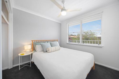 a white bedroom with a bed and a window at Alma Beach Haven in North Haven