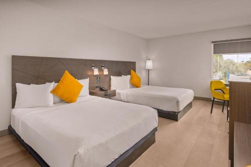 a hotel room with two beds with yellow pillows at B&B Hotel Miami Airport in Miami