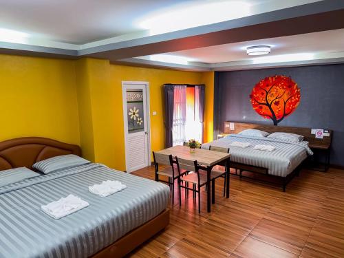 a hotel room with two beds and a table and a dining room at Nangnon Hill Hug Hotel in Ban Pa Muat