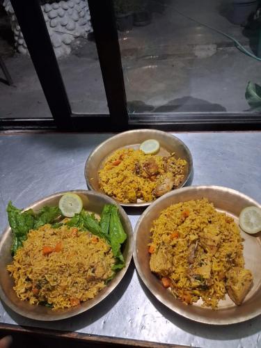 Drei Teller mit Reis und Salat standen auf der Theke. in der Unterkunft Riverside hostel in Ghanpokhara