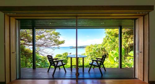 a screened in porch with a table and two chairs at Villa SACHIIBARU 浜辺の茶屋 の 宿 in Nanjo