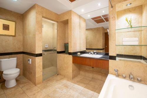 a bathroom with a toilet and a shower and a sink at Aryaduta Manado in Manado