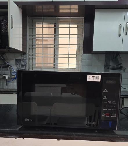 a microwave oven sitting on a counter in a kitchen at 3bhk Near kodapur-Hitex Exhibition&Shilparamam Art in Hyderabad