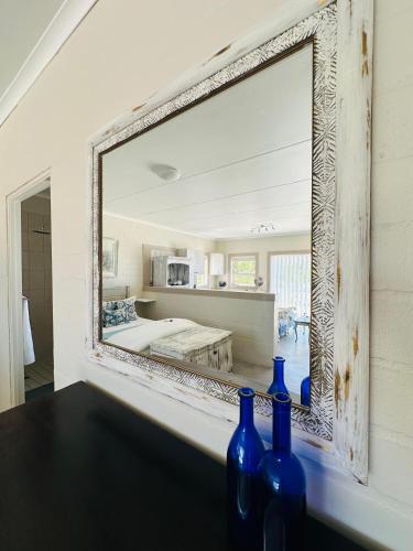 a mirror on a wall with blue bottles on a table at WestBed in Langebaan