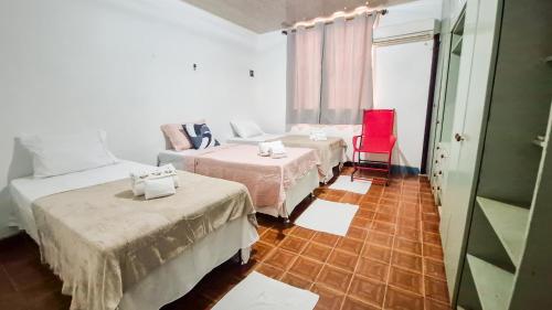 ein Zimmer mit zwei Betten und einem roten Stuhl in der Unterkunft Pousada in Belém