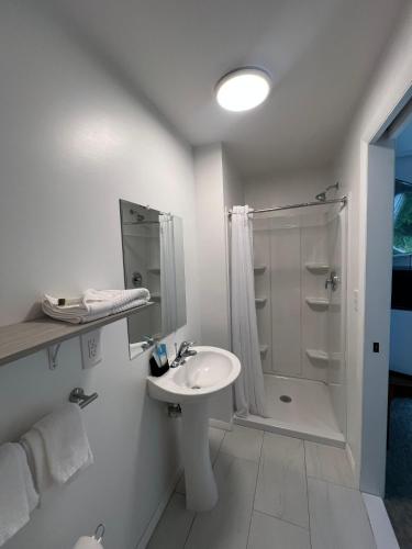 a white bathroom with a sink and a shower at Lyn Aire Motel - Lake George in Lake George