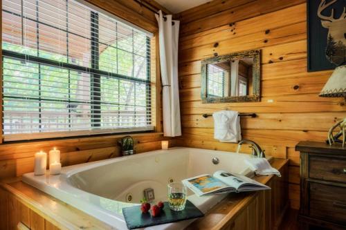 a bath tub in a wooden bathroom with a window at Joy's Retreat Cabin in Sevierville