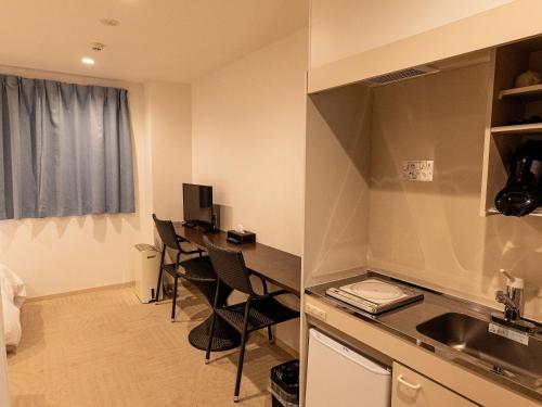 a room with a kitchen with a desk and chairs at HOTEL PAiKAJi in Ishigaki Island