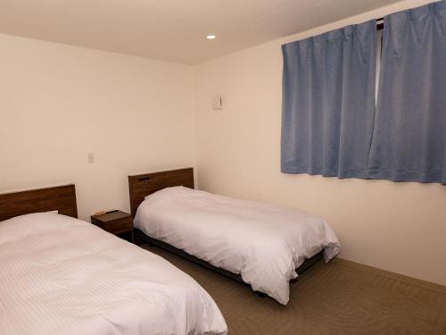 a bedroom with two beds and a blue curtain at HOTEL PAiKAJi in Ishigaki Island