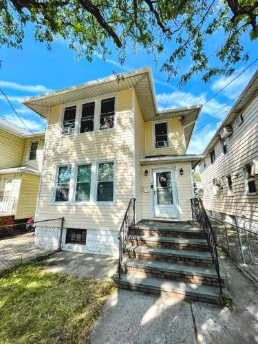 a yellow house with stairs in front of it at Entire Beautiful 1BR for You! [R] in Whitestone