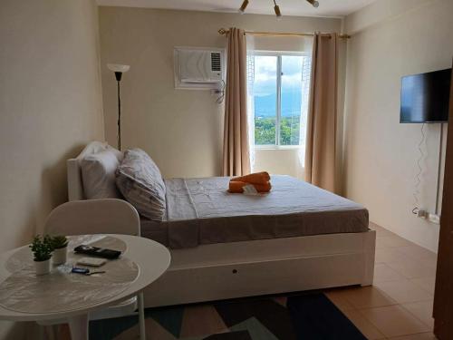 a bedroom with a bed and a table and a window at Mountain View Studio at Marina Spatial - 300Mbps, Pool, City Centre in Dumaguete