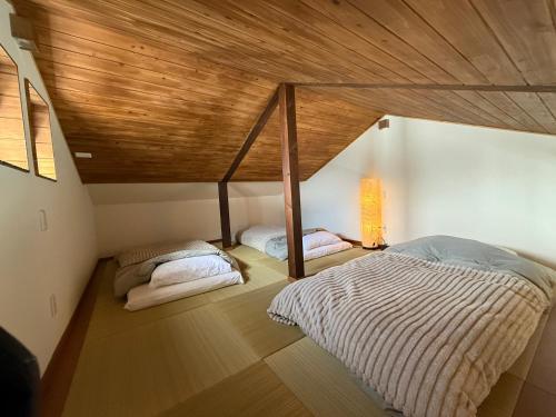 two beds in a room with a wooden ceiling at New Hoshiba in Nozawa Onsen