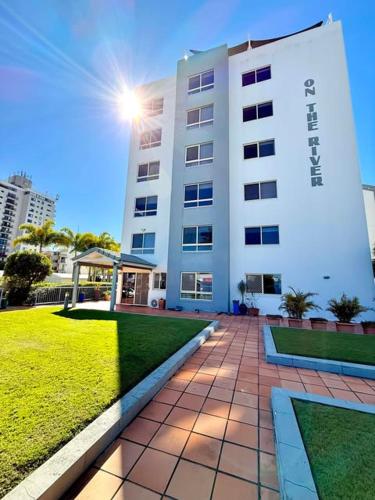 a large white building with the sun shining behind it at On The River Apartments in Maroochydore