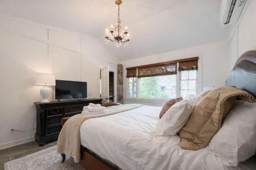 a bedroom with a bed with a television and a chandelier at Honeymoon Cottage Chateau DuMont in Banner Elk