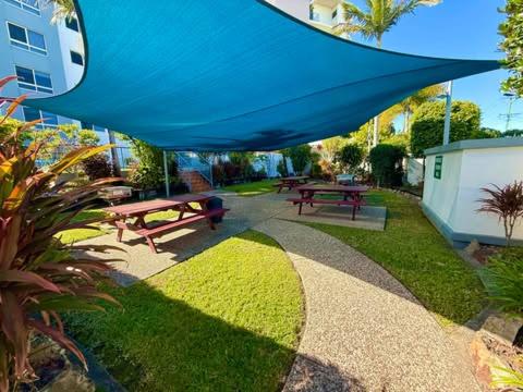 a picnic area with benches and a blue umbrella at On The River Apartments in Maroochydore