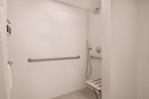 a white bathroom with a shower and a bench at B&B HOTEL Orlando International Drive near Universal - Newly Renovated! in Orlando
