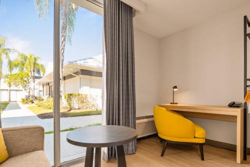 a living room with a desk and a yellow chair at B&B HOTEL Orlando International Drive near Universal - Newly Renovated! in Orlando