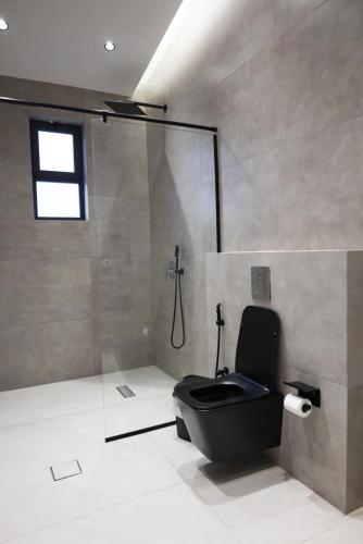 a bathroom with a black toilet and a shower at Amora Villa in Al Rama