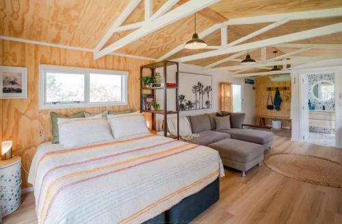 a bedroom with a large bed and a couch at Mangapiko Cabin in Pirongia