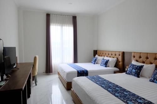a hotel room with two beds and a flat screen tv at Grand Elhajj Banten in Tjipondoh Tiga