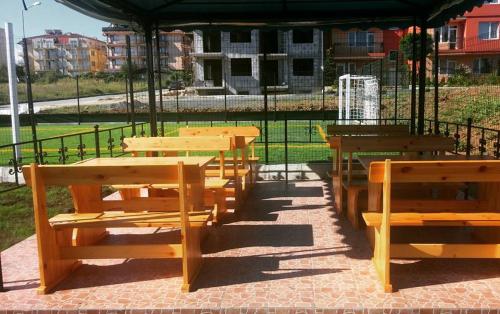 a group of wooden tables and benches in a park at Guest House ASK in Primorsko
