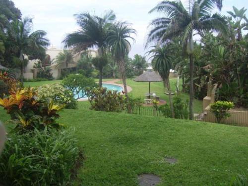 a view of a yard with a pool and palm trees at Mallorca 13 Duplex in Umdloti