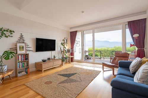 a living room with a blue couch and a tv at Eastern Shore Escape - Panoramic Modern Comforts in Hobart