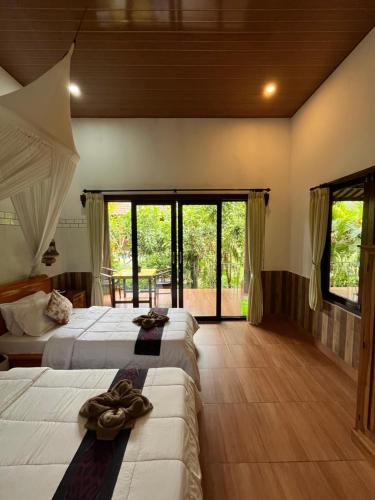 a bedroom with two beds and a large window at Khrisna Hs and Cottages in Sidemen