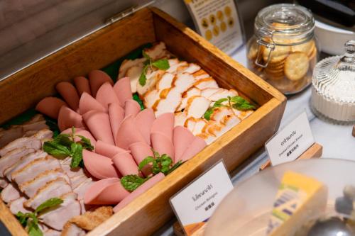 a tray of sushi in a wooden box on a table at Centara Hotel Hat Yai in Hat Yai