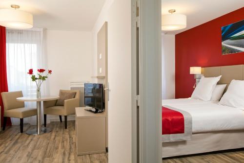 バニューにあるセジュール＆アフェール パリ バニューのベッド、テーブル、テレビが備わるホテルルームです。