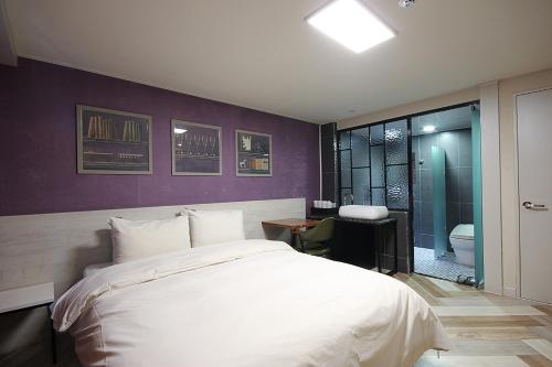 a bedroom with a white bed and a bathroom at Hotel Mondavi in Mokpo