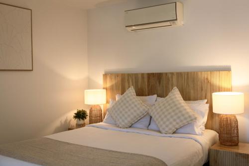 a bedroom with a bed with pillows and two lamps at At The Sound Noosa in Noosaville