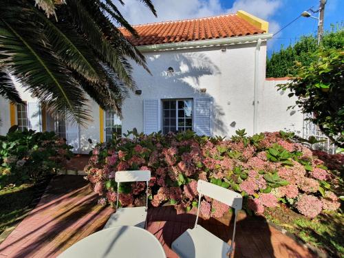 a patio with chairs and flowers in front of a house at Villa Cedros in Santa Cruz das Flores