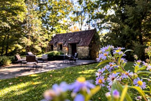 a garden with a stone house and some flowers at Hideaway Cottage Chateau DuMont in Banner Elk