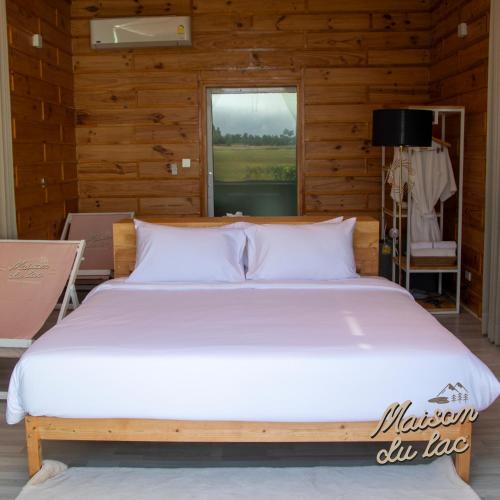 a bedroom with a large bed in a wooden room at Maison Du Lac The Panoramic Glass Lodge in Wang Nam Khieo