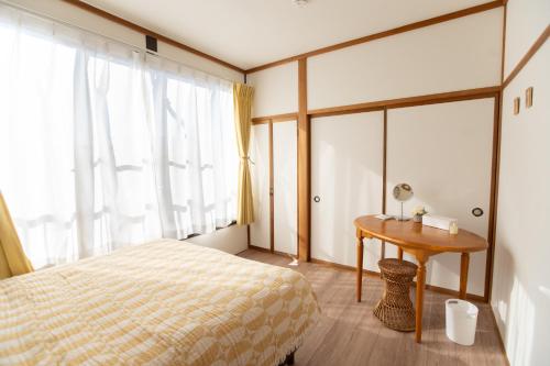 a bedroom with a bed and a table and a window at Tsugumi Entire House Rental in Matsumoto in Matsumoto
