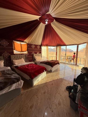 a bedroom with three beds and a large tent at joy of life Camp in Wadi Rum