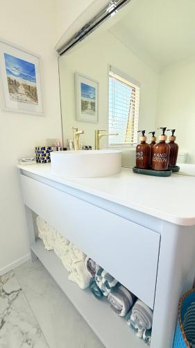 a bathroom with a sink and a mirror at Beach Apartment in Papamoa