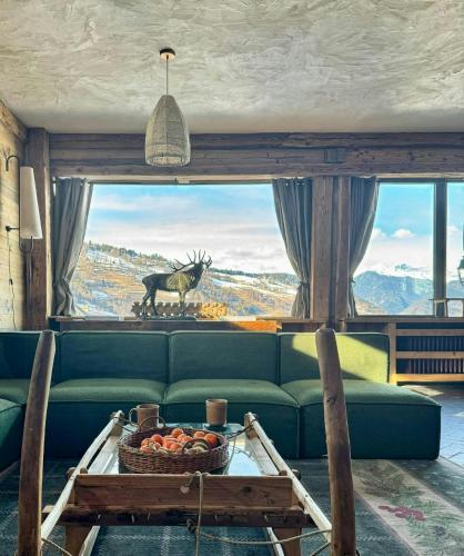 a living room with a green couch and a large window at Former Hotel Transformed Into Chalet In Valmorel in Les Avanchers