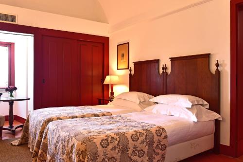two beds in a hotel room with red walls at Pousada Convento de Beja in Beja
