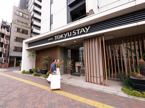 two people walking out of a hotel with their luggage at Tokyu Stay Shimbashi - Ginza area in Tokyo